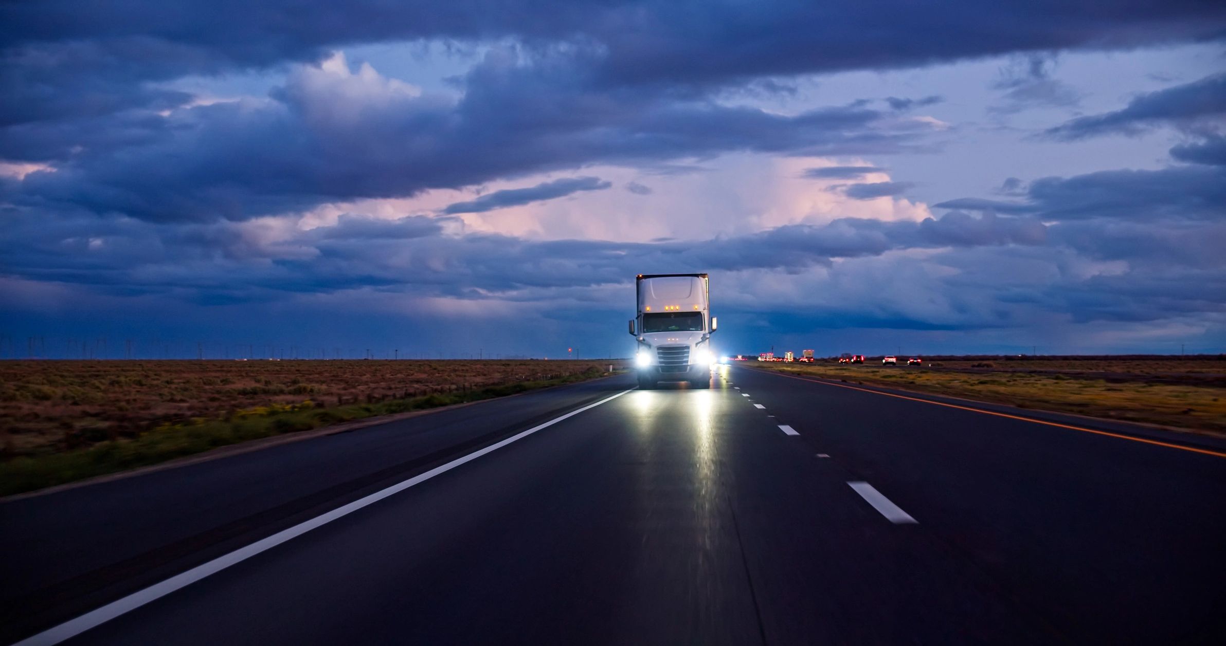 Commercial truck driving on interstate at sunset